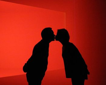 Silhouette couple standing against red wall