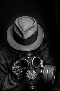 Close-up of man wearing gas mask against black background