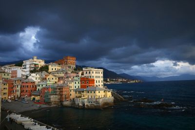 City at waterfront against cloudy sky