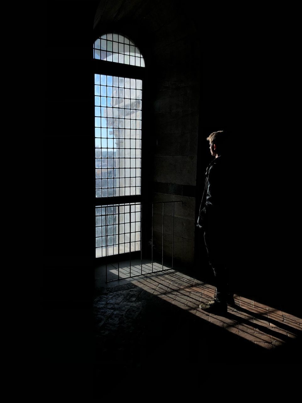 SIDE VIEW OF MAN STANDING BY WINDOW