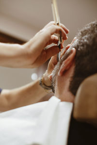 Low angle cropped hands of barber shaving man