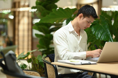 Young woman using laptop while sitting at cafe