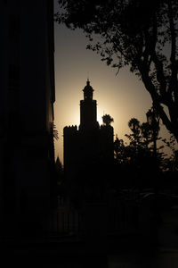 Silhouette trees and buildings against sky at dusk