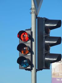 Low angle view of road signal against clear blue sky