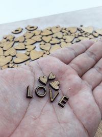 Cropped hand of man holding love text with heart shapes on table