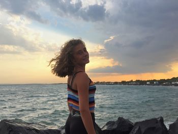 Woman looking at sea against sky during sunset