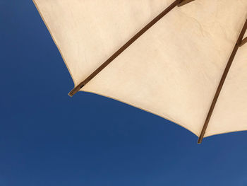 Low angle view of parasol against clear blue sky