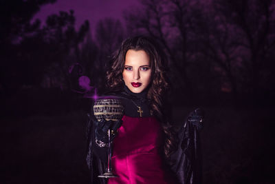 Portrait of young woman standing against purple outdoors