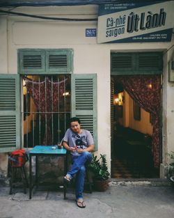 Full length of man sitting against building