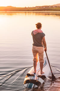 Young woman stand up paddling sup at sunset, lake wallersee, austria