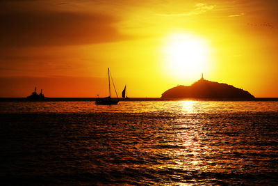 Silhouette sailboats in sea against sky during sunset