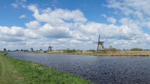 Traditional windmill on shore against sky