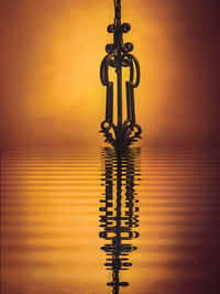 Close-up of silhouette pole against sea during sunset