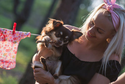 Close-up of smiling woman carrying chihuahua