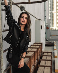 Portrait of young woman standing against wall
