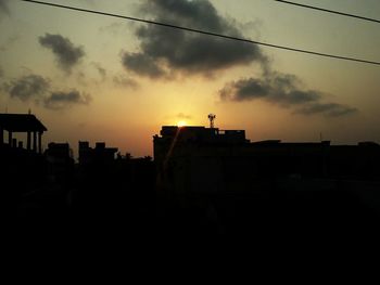 Silhouette buildings against sky at sunset