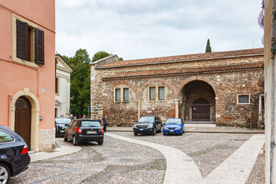 Cars on road by buildings in city against sky