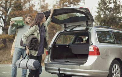 Woman closing car boot while camping with man