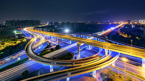 Illuminated multiple lane highway in modern city against sky