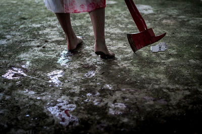 Cropped image of woman wearing dress while holding axe covered with blood