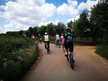 People riding bicycle on road against sky