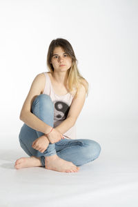 Portrait of young woman sitting against white background