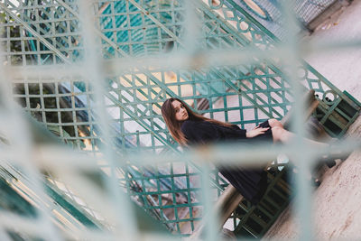 Portrait of woman standing by fence