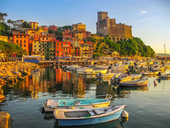 Boats moored on river by buildings against sky