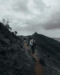 Rear view of men on mountain against sky