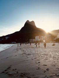 People at beach against sky during sunset