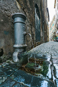 Water fountain by street against wall in city