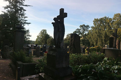 Stone cross on cemetery against sky