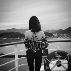 Rear view of woman standing on boat against sky