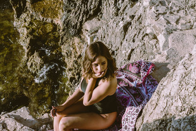 Portrait of smiling young woman sitting on rock