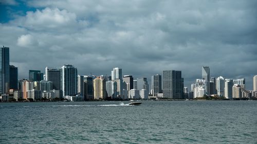 Sea by cityscape against sky