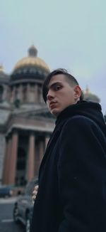 Portrait of young man standing against saint isaac's cathedral in saint petersburg, russia. 