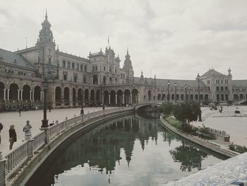 Arch bridge over canal amidst buildings in city