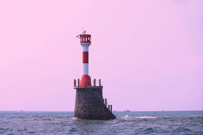 Lighthouse by sea against sky