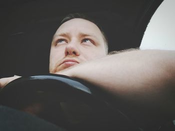 Low angle view of thoughtful man sitting in car