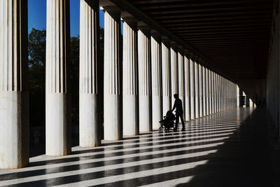 Man with baby stroller in colonnade
