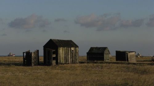 House on field against cloudy sky