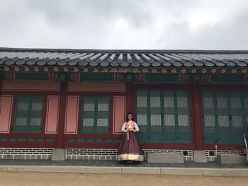 Full length of young woman wearing traditional clothing while standing against house