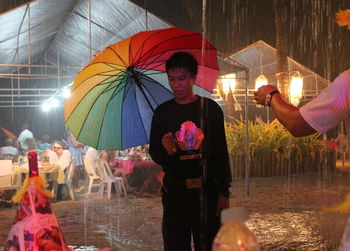 Man holding umbrella standing with multi colored umbrellas
