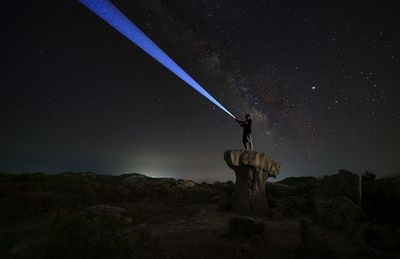 Man standing on rock against sky at night