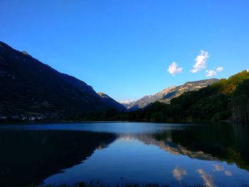 Scenic view of lake and mountains against blue sky