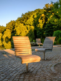 Empty bench in park against sky