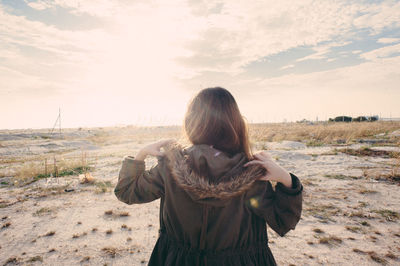 Young woman standing on landscape against sky