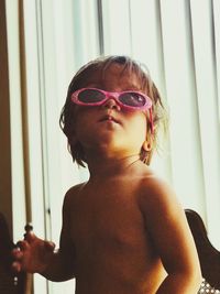 Portrait of shirtless young man wearing sunglasses at home