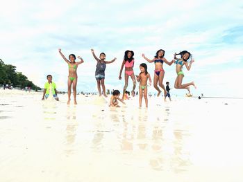 Children playing on beach against sky