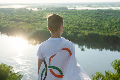 Rear view of man standing by lake against sky